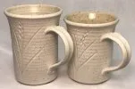 Two matte glazed mugs on a speckled body