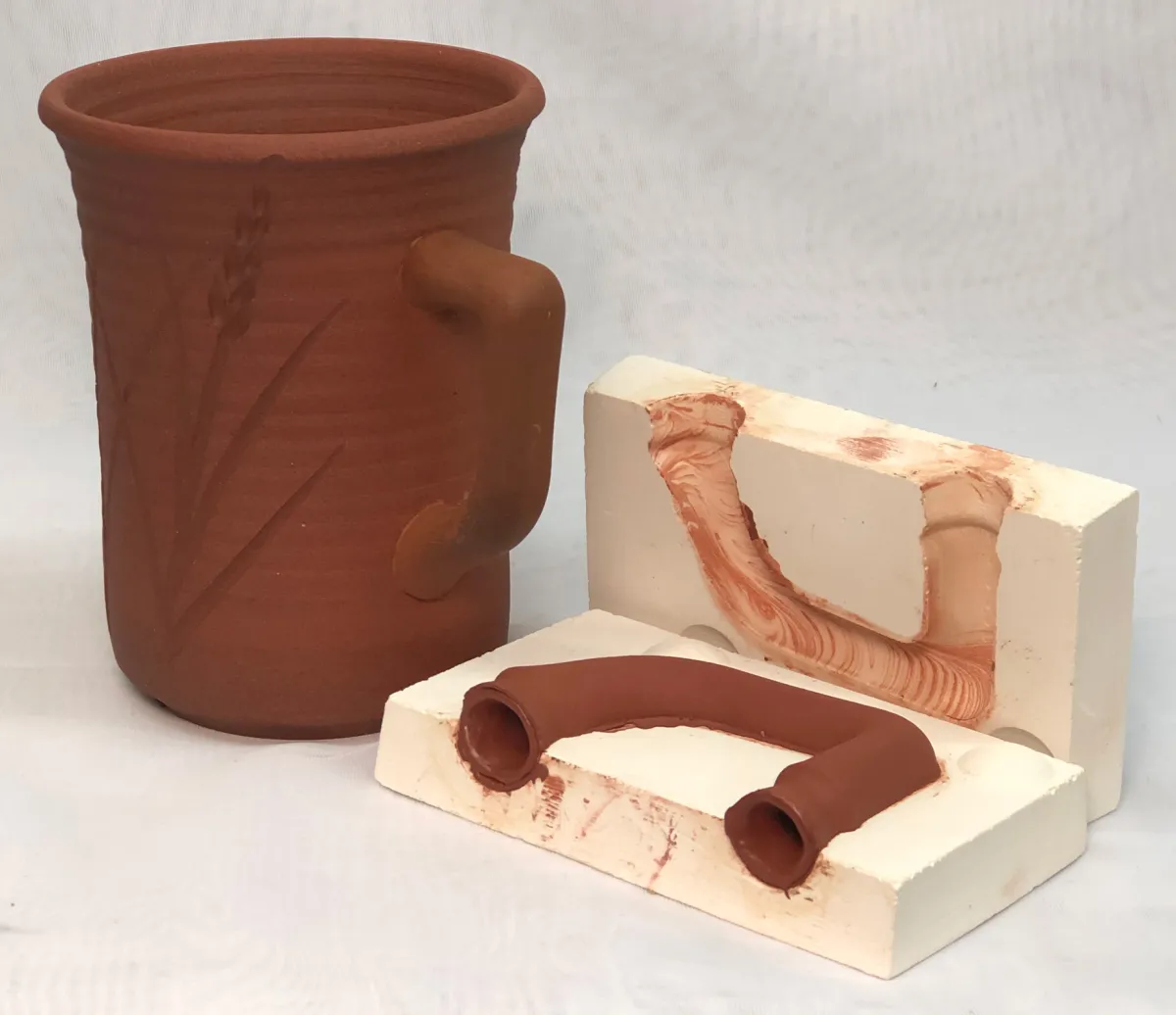A red cone 6 thrown glazeless coffee mug with a cast handle
