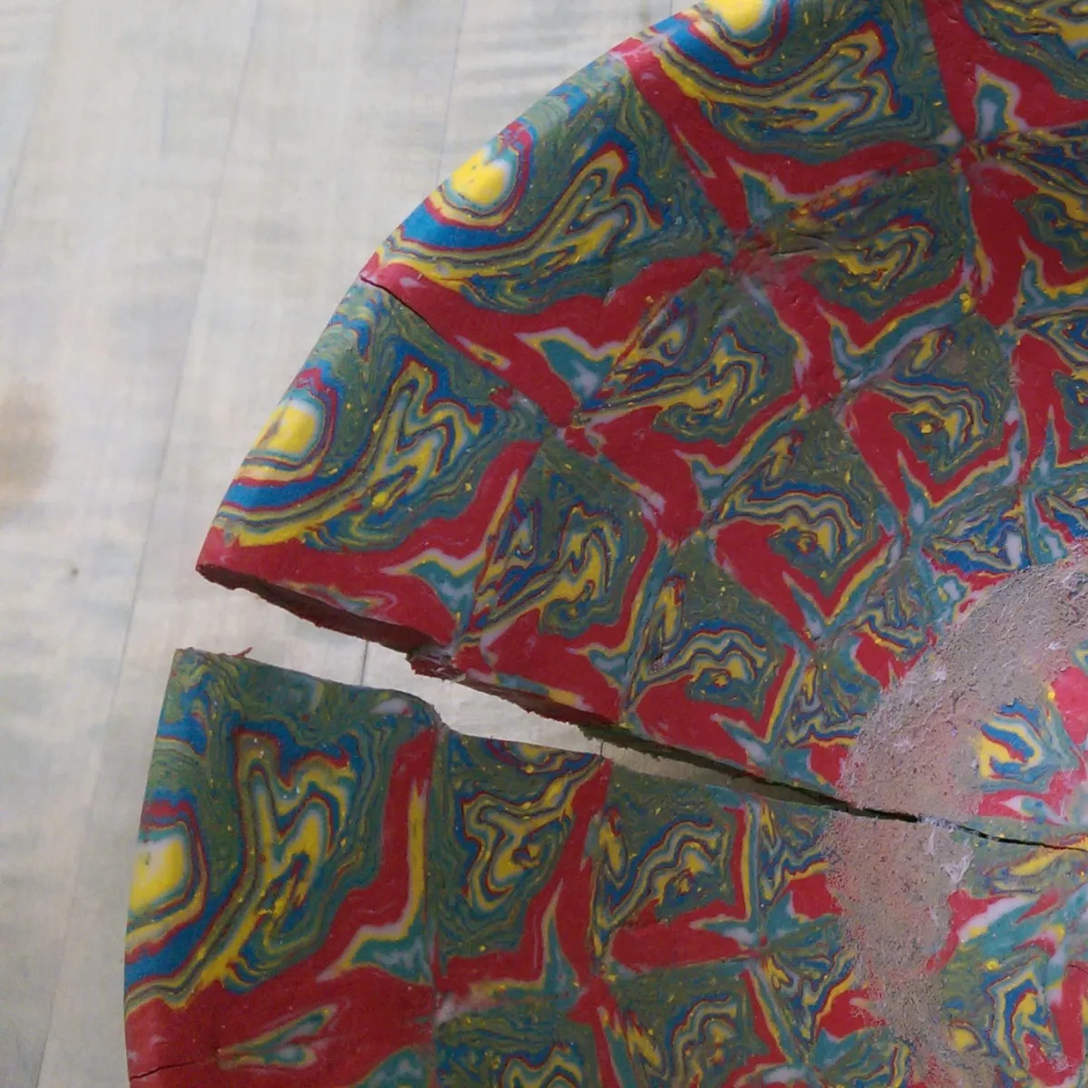 A multicolored marbled porcelain bowl has cracked at the boundary between red and green