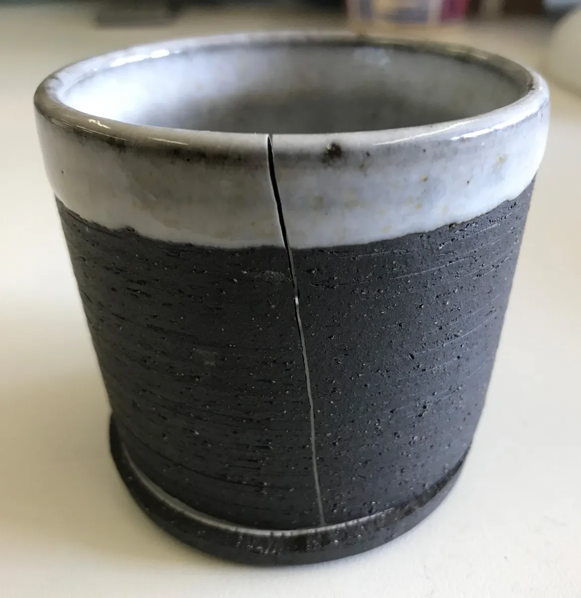 A glaze is pushing outward from the inside of this cone 6 cup