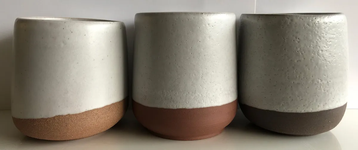 Three pottery mugs, two having glaze pinholes
